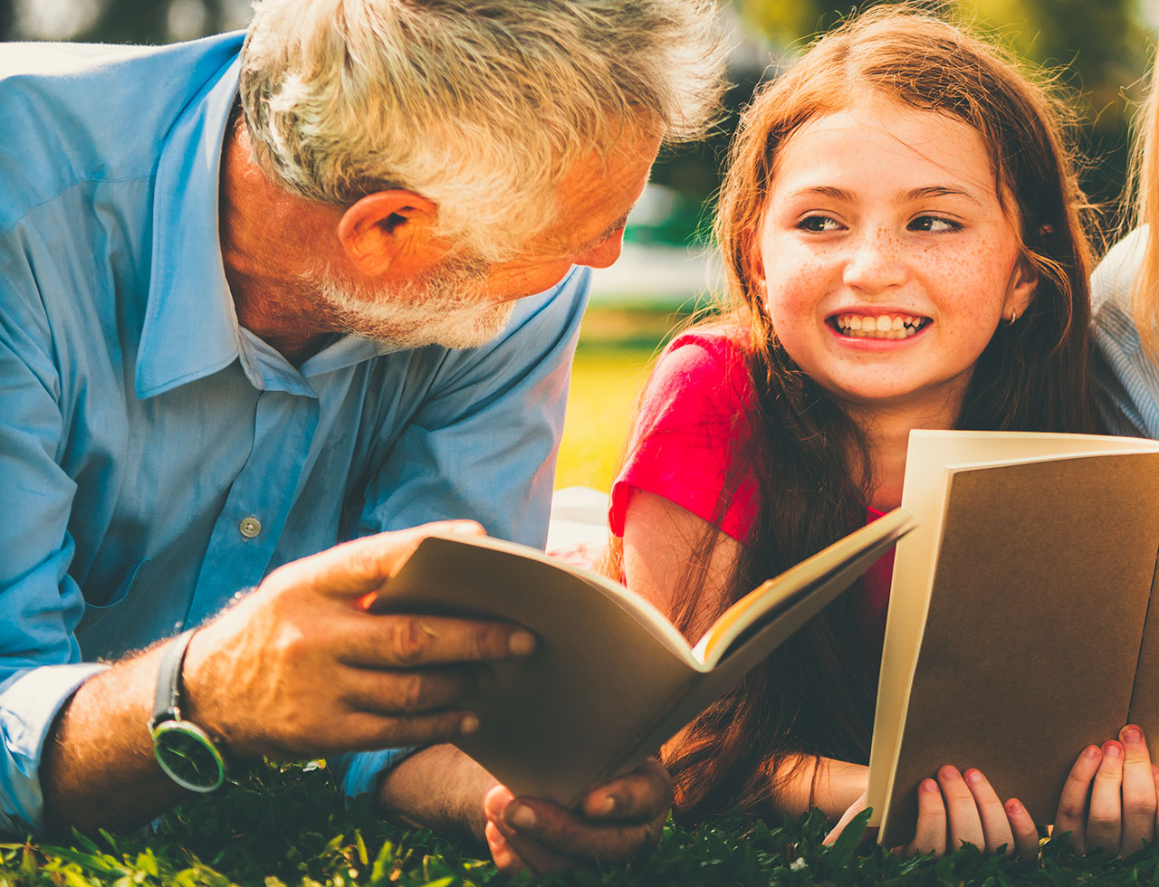 Happy family read books together in park garden.
