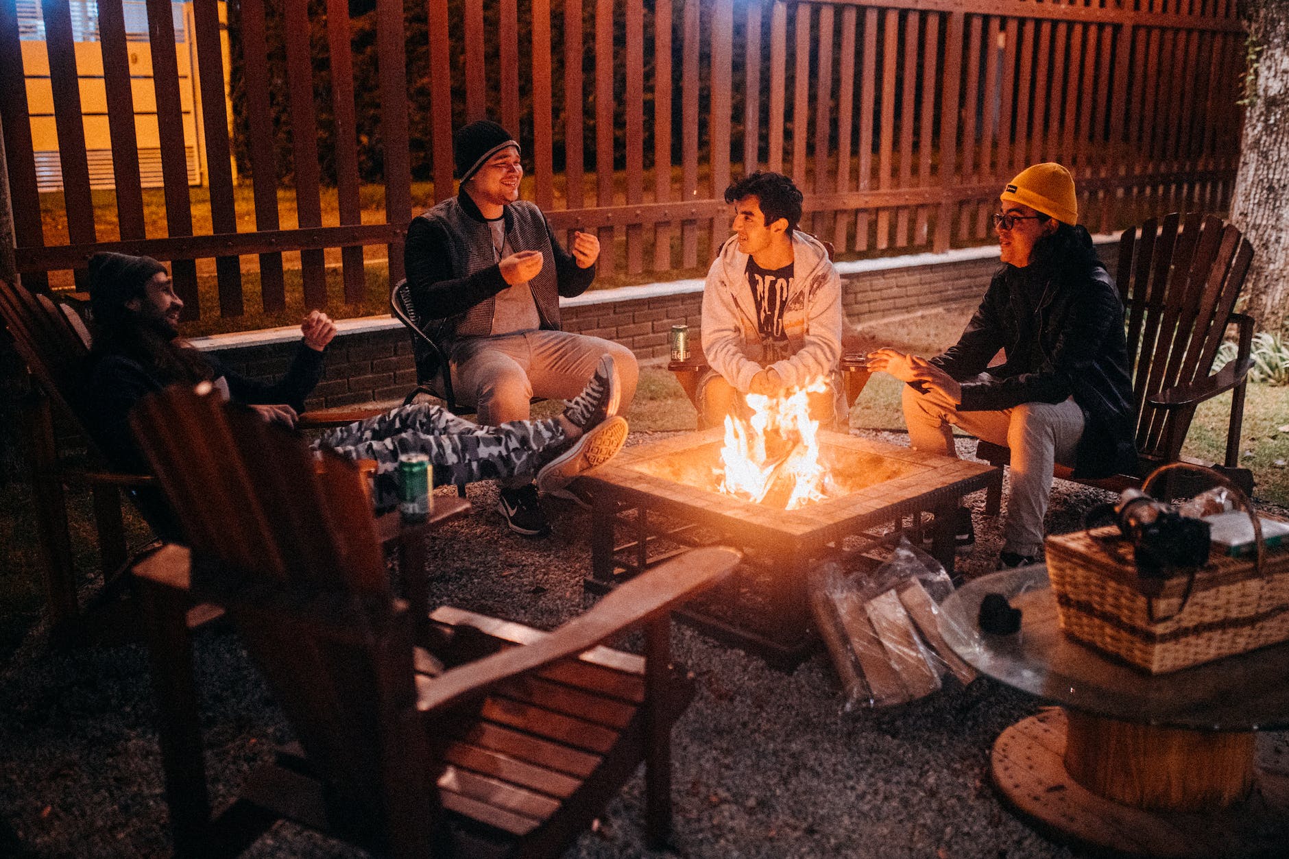 smiling friends speaking against bright flame in camp at night
